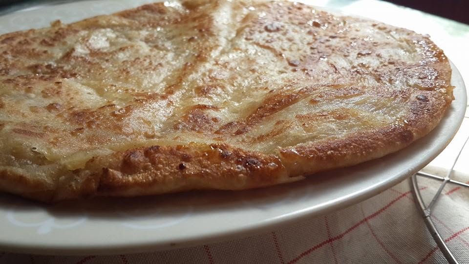 A freshly cooked meethi roti, a sugar-and-ghee paratha, served on a plate.