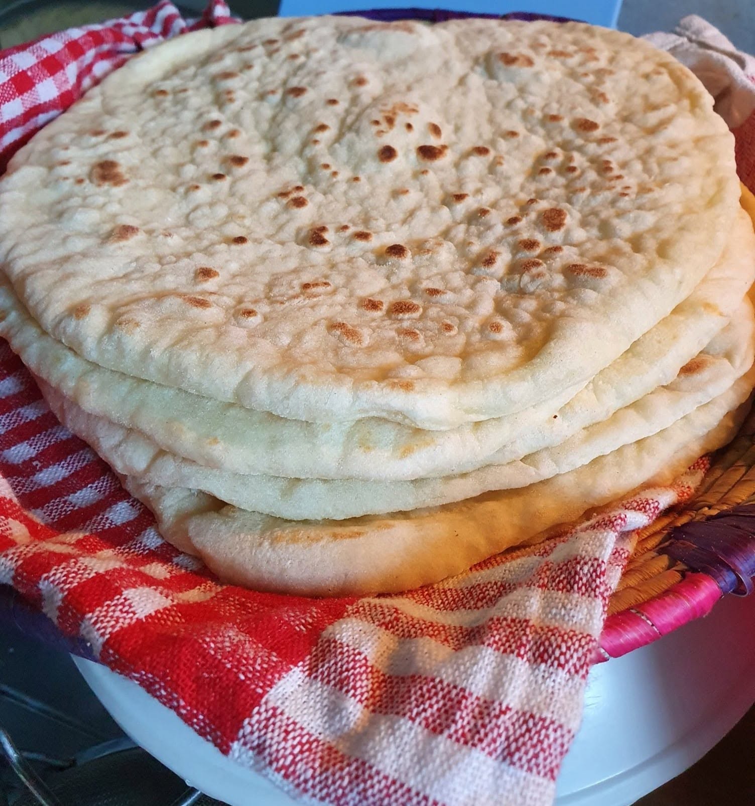 Soft homemade naan cooked on a tawa.